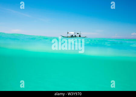 Über - unter Aufnahme der Philippinischen Auslegerboot in türkisfarbenen Meer Wasser vor der Küste der Insel Boracay, Aklan Provinz Western Visayas, Philippinen Stockfoto