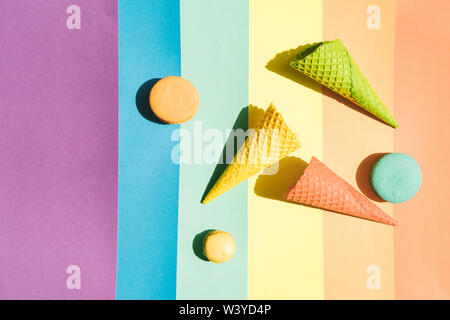 Waffeln für Eis und Makronen auf einem Regenbogen Hintergrund mit einem harten Schatten auf der Oberfläche von hellem Sonnenlicht Stockfoto