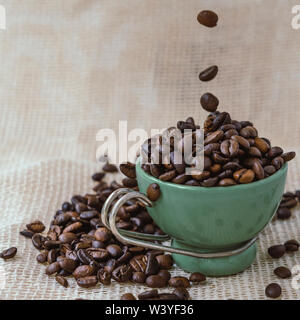 Grüne Schale unter eine Menge Kaffee Bohnen auf Jute Tasche. Stockfoto