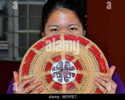 Junge malaysischen Bidayuh Frau mit schönen Augen verbirgt ihr Gesicht hinter dem unteren Sarawakian Version des berühmten Asiatischen konische Hut. Stockfoto