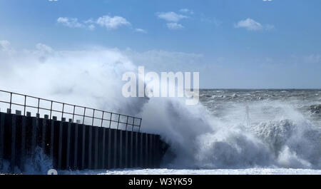 Dramatische stürmischen Meer gegen eine Hafenmauer, Gischt und Wellen hoch in die Luft, das Meer und ein blauer Himmel in der Ferne, Seaford, East Sussex, Stockfoto