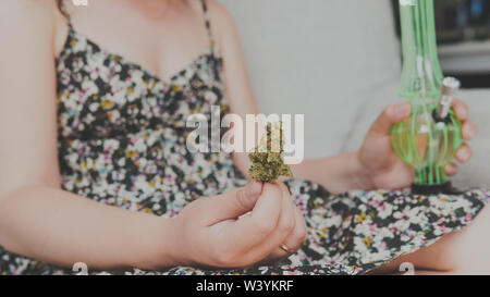 Der junge Mensch in seiner Hand medizinisches Marihuana Knospen und Bong. Die medizinische Verwendung von Cannabis rauchen mit Bong. Marihuana ist ein Konzept der Kräutermedizin Stockfoto