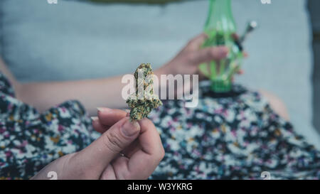 Der junge Mensch in seiner Hand medizinisches Marihuana Knospen und Bong. Die medizinische Verwendung von Cannabis rauchen mit Bong. Marihuana ist ein Konzept der Kräutermedizin Stockfoto