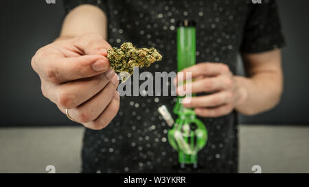 Der junge Mensch in seiner Hand medizinisches Marihuana Knospen und Bong. Die medizinische Verwendung von Cannabis rauchen mit Bong. Marihuana ist ein Konzept der Kräutermedizin Stockfoto