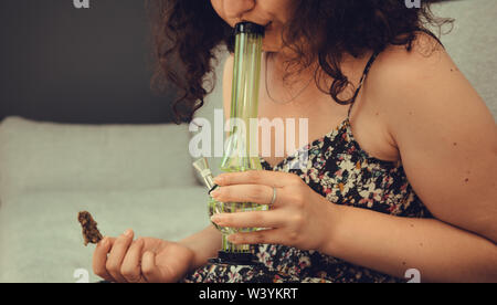 Der junge Mensch in seiner Hand medizinisches Marihuana Knospen und Bong. Die medizinische Verwendung von Cannabis rauchen mit Bong. Marihuana ist ein Konzept der Kräutermedizin Stockfoto