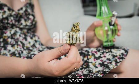 Der junge Mensch in seiner Hand medizinisches Marihuana Knospen und Bong. Die medizinische Verwendung von Cannabis rauchen mit Bong. Marihuana ist ein Konzept der Kräutermedizin Stockfoto