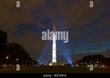 Leute schauen auf Projektion der Saturn V Rakete auf der Ostseite des Washington Monument in der 50-Jahr-Feier der Apollo 11 Mondlandung. Stockfoto
