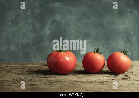 Frische Tomaten auf einer alten Eiche Holztisch, schöne graue Wand Hintergrund. Stockfoto