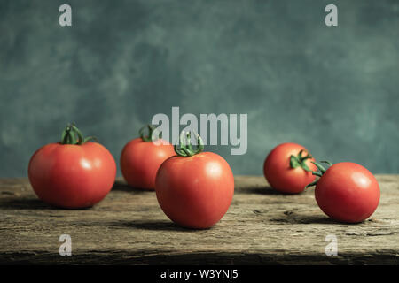 Frische Tomaten auf einer alten Eiche Holztisch, schöne graue Wand Hintergrund. Stockfoto