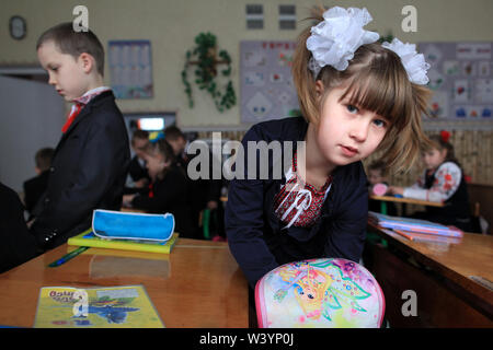 Einen Ukrainischen elementare Schülerin im Klassenzimmer ihr Material für die Lektion vorbereiten während der Pause. Radinka, Kiev Oblast, Ukraine Stockfoto