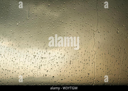 Regen fällt auf Fenster Glas mit Bewölkt/düsteren Himmel Hintergrund. Hf-regnerischen Hintergrund mit beige, neutralen Farben, Wassertropfen Textur Stockfoto