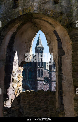 St Davids Cathedral Pembrokeshire. Von einem der Rundbogenfenster in die Ruinen von Bishops Palace gesehen. Stockfoto