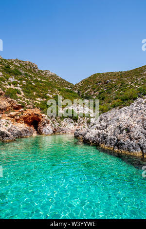 Kleine, paradiesische Bucht von Porto Limnionas mit Blick auf das klare, türkisfarbene Wasser und Fels mit Büschen, Zakynthos, Griechenland Stockfoto