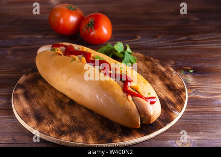 Hausgemachtes Essen Hotdog gefüllt mit Wurst und Gemüse in Holz- Platte auf holztisch Nahaufnahme Stockfoto