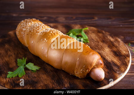 Hausgemachtes Essen Hotdog gefüllt mit Wurst und Gemüse in Holz- Platte auf holztisch Nahaufnahme Stockfoto