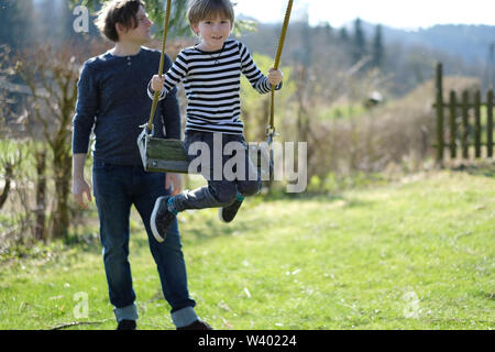 Ein Mann rollt mit seinem Sohn auf einer hängenden Schwingen Stockfoto