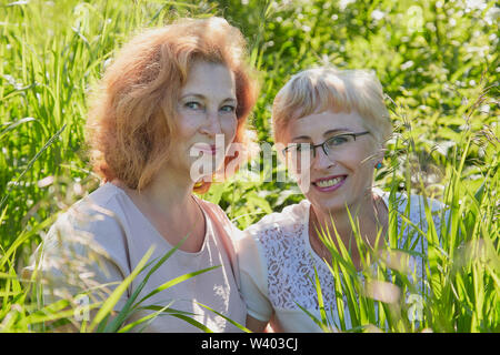 Zwei weibliche Freunde, Spaß an der Natur. Mollig und schlank Frauen mittleren Alters Rentner in ein grünes Feld Stockfoto