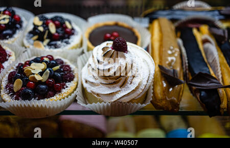 Desserts, Gebäck, Kuchen und verschiedenen Süßigkeiten zu Cafeteria und Coffee shop Fenster. Viele verschiedene frische leckere Desserts Mousse, souffle, ecler Kuchen. Stockfoto