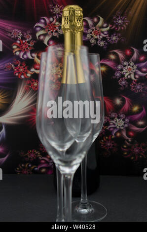 Eine Flasche Sekt, Champagner, Wein, hinter Champagner Gläser. Der dunkle Hintergrund mit abstrakten bunte Blumen. Stockfoto