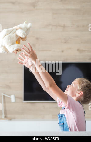 Schöne Mädchen auf dem Sofa umarmen Teddybär. Das Konzept einer glücklichen Kindheit, Spiel in der Familie. Stockfoto