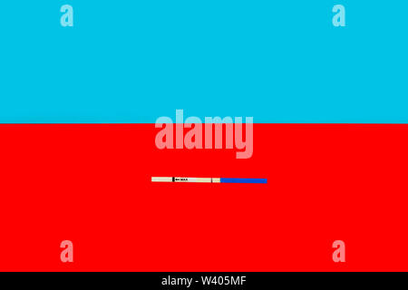 Der Test ein Streifen auf die Schwangerschaft mit negativem Ergebnis auf einem roten Hintergrund im unteren Bereich einen Schuß, von oben kopieren Speicherplatz auf einem blauen Hintergrund. Stockfoto