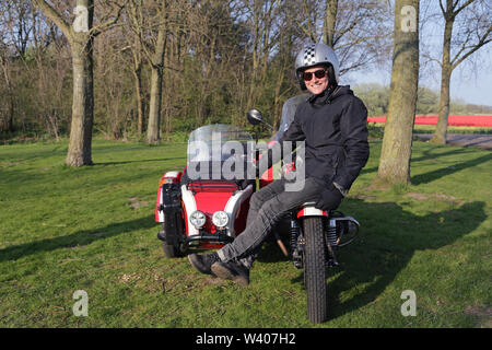 Junge Frau sitzt auf der vorderen Reifen für Ihr Motorrad außerhalb Stockfoto