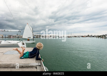 Junges Kind beobachten ein Segelboot in Napier, Neuseeland Stockfoto