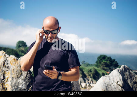 Glatzköpfige Mann mit Wireless Headset und Mobiltelefon. Stockfoto