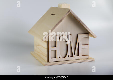 Hausgemachte Holzhaus Sparschwein mit der Inschrift nach Hause. Haus auf einen soliden Hintergrund. Stockfoto