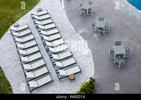 Reihen von Liegen und Tischen am Pool in einem Resort am Strand Stockfoto