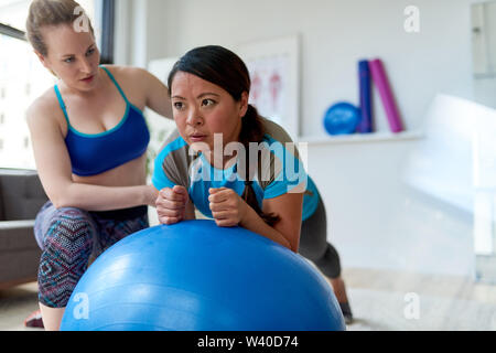 Kaukasische Frau Physiotherapeutin ein Training Session eine Zwischenbilanz nach chinesischen weiblichen Patienten auf einem Gymnastikball Stockfoto