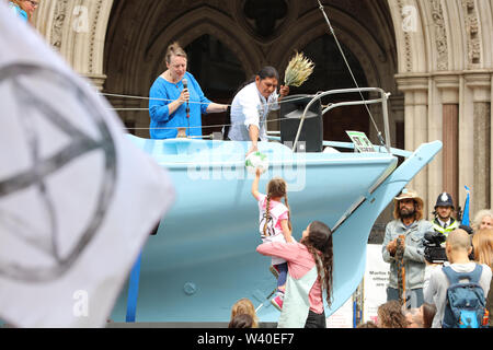 London, Großbritannien. 15. Juli 2019. Aussterben Rebellion Aktivist und Sänger form Ecuador Händen eine Kugel zu einem Kind am Protest des Climate Action Group vor dem königlichen Gerichten auf dem Strand, London. Credit: Joe Kuis/Alamy Nachrichten Stockfoto