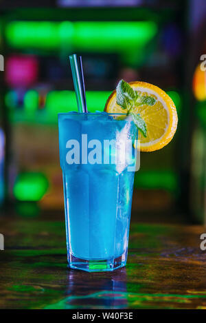 Blue Cocktail in ein hohes Glas Glas mit einer Scheibe Orange. Bunten Cocktail auf der dunklen Rückseite. Cocktail auf einen farbigen Hintergrund in ein hohes Glas. Stockfoto