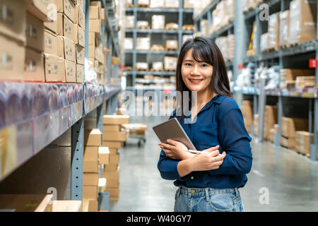 Junge asiatische Frau Prüfer oder Trainee Personal Arbeit suchen und prüft die Anzahl der Elemente speichern von digitalen Tablet. Asiatische Eigentümer oder Small Business conce Stockfoto