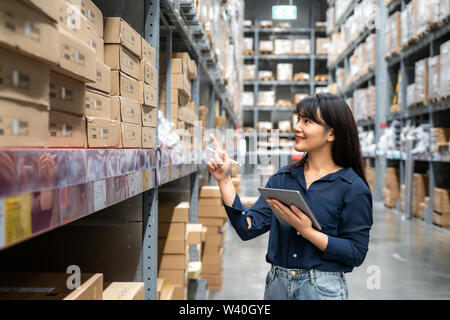 Junge asiatische Frau Prüfer oder Trainee Personal Arbeit suchen und prüft die Anzahl der Elemente speichern von digitalen Tablet. Asiatische Eigentümer oder Small Business conce Stockfoto