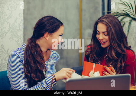 Junge schöne Mädchen sitzen im Cafe mit ihrem Freund und ein Geschenk. Stockfoto