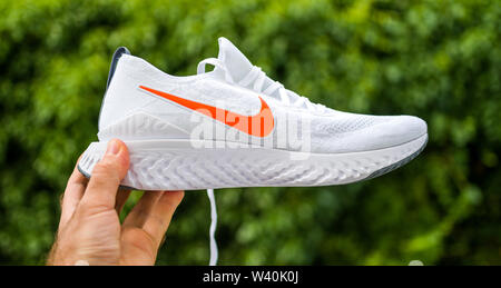 Paris, Frankreich - Apr 8, 2019: Athlet mann Hand präsentieren neue Laufschuhe Nike Epic reagieren Flyknit 2 Seitenansicht mit rotem Schriftzug Stockfoto