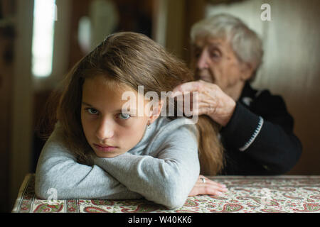 Eine ältere Frau Geflechte ihre Enkelin Haar. Stockfoto