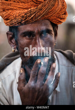 PUSHKAR, INDIEN - ca. November 2018: kameltreiber Rauchen am frühen Morgen in der Pushkar Kamel Messe. Es ist einer der größten Kamel der Welt messen. Stockfoto