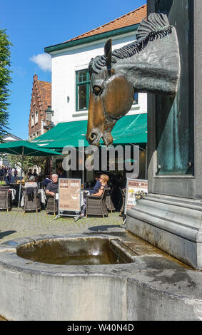 Brügge, Flandern, Belgien - 17. Juni 2019: grauen Stein Wasserpumpe mit Pferdekopf als Wasserhahn besonders für Pferde Kutschen in der Nähe der Beginenhof. Menschen Stockfoto