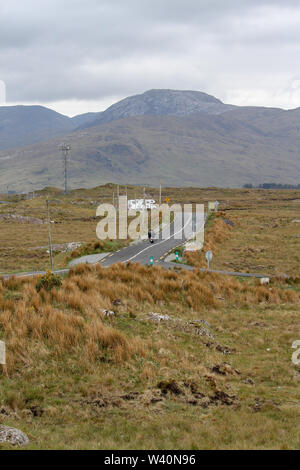 Straße Öffnen über Land im Westen von Irland mit einem Motorradfahrer und Camper auf einer Landstraße in Richtung Connemara in der Grafschaft Galway Moor. Stockfoto