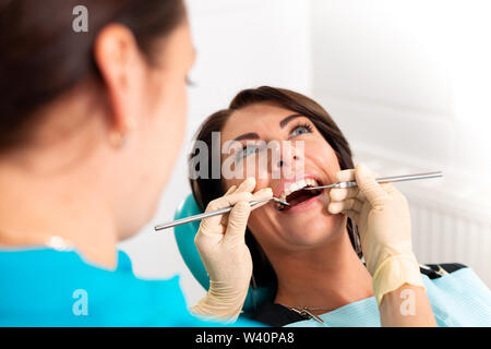 Putting Zahnspangen zu den Zähnen der Frau im zahnmedizinischen Büro. Zahnarzt untersuchen Patientin mit Klammern in der Zahnarztpraxis. Nahaufnahme einer Junge Stockfoto