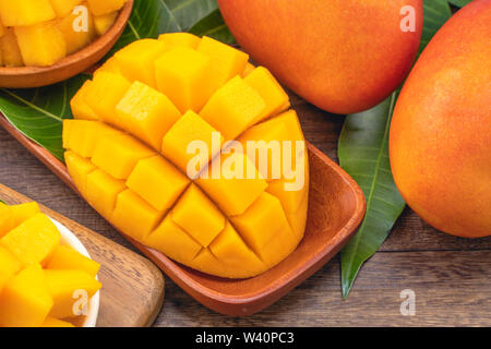 Frische gehackte mango Würfel auf Holz Schneidebrett und rustikales Holz Hintergrund. Tropischer Sommer Obst Konzept, Nahaufnahme, Makro, kopieren. Stockfoto