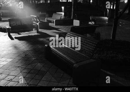 Bänke im Park nach dem Regen mit einem Spotlight im Hintergrund Stockfoto