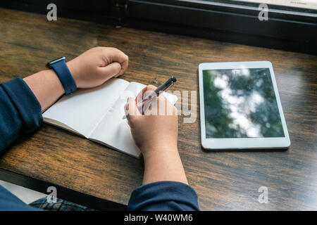 Asiatische menschlichen Hand mit Stift und neben Tablet schreiben Stockfoto