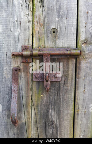 Rusty ländlichen handgefertigte Schloss im Alter von Bemoosten Holz- dorf Tür. Im 19. Jahrhundert. Sonnigen Tag im Freien Nahaufnahme Stockfoto