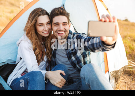 Foto von glückliches junges Paar draußen im Freien alternative Ferienhäuser Camping nehmen selfie per Handy. Stockfoto