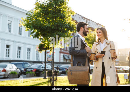 Portrait der kaukasischen Geschäft Paar der Mann und die Frau in der gesellschaftsmode trinken Kaffee zum Mitnehmen und zusammen reden während der Sitzung am Ort Straße Stockfoto