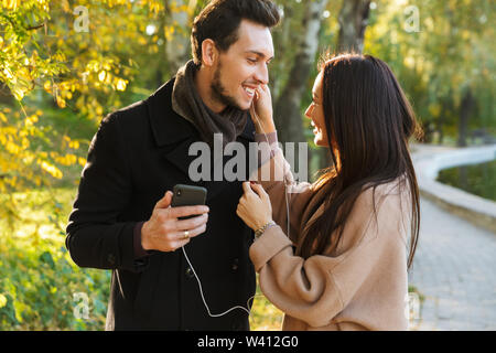 Schöne junge Paar in Liebe Ausgabe Zeit zusammen im Park im Herbst, Wandern, Musik hören mit Kopfhörern Stockfoto
