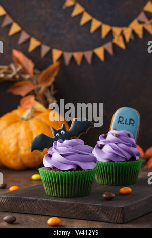 Bat und Tombstone Lebkuchen Plätzchen als Cupcake Dekorationen. Festliche Halloween Festlichkeiten auf einem dunklen Hintergrund mit kopieren. Stockfoto